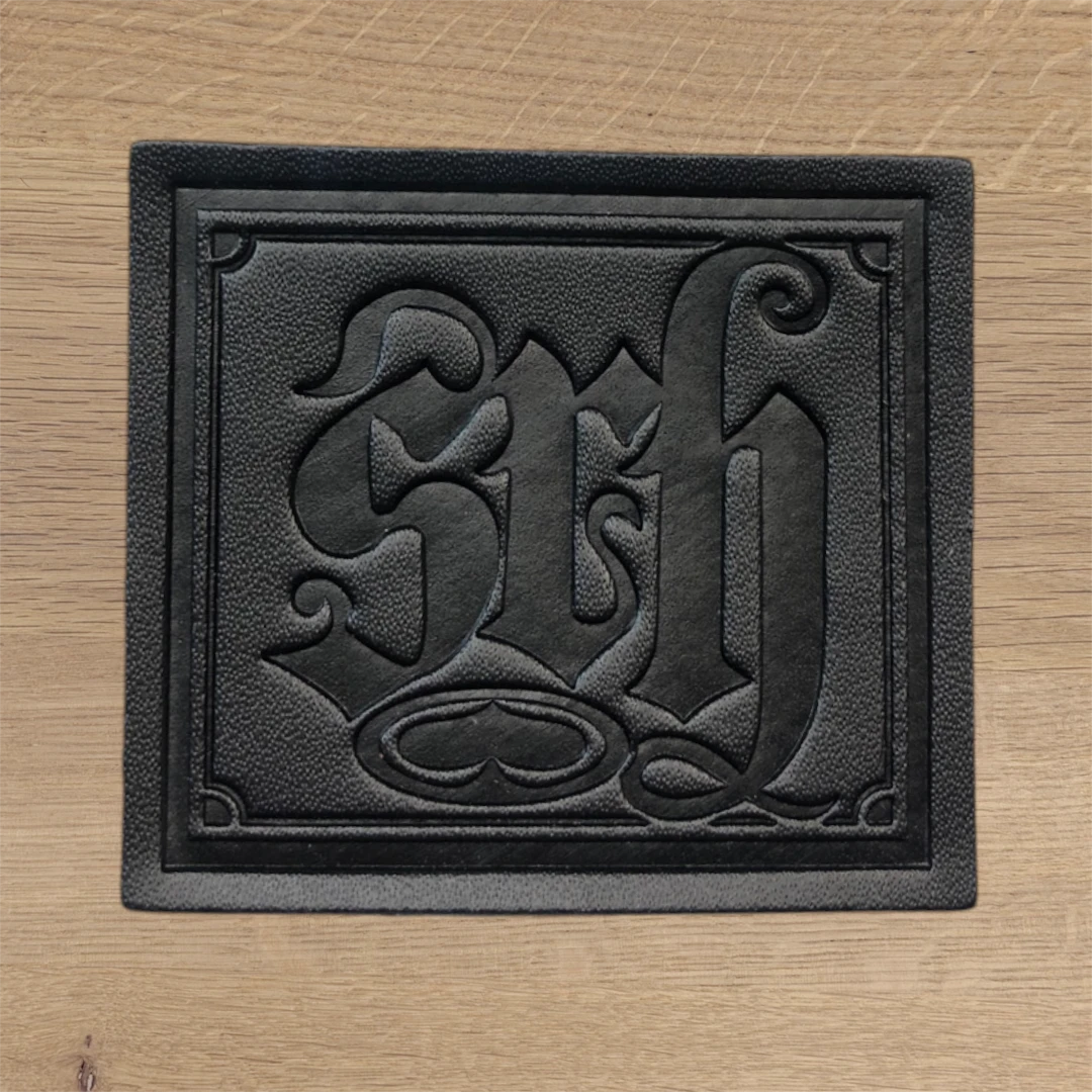black leather patch with debossed gothic monogram design