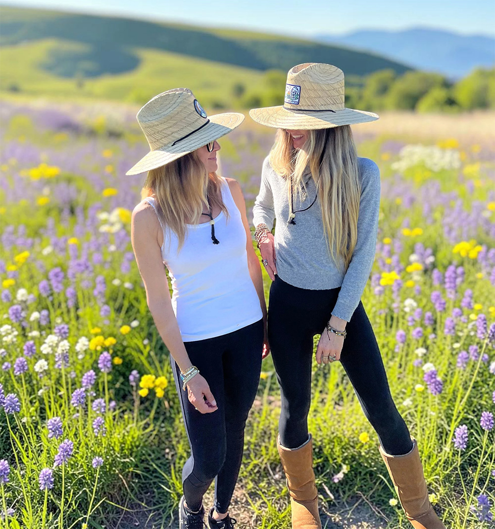 two women wearing natural straw lifeguard hats with custom patches